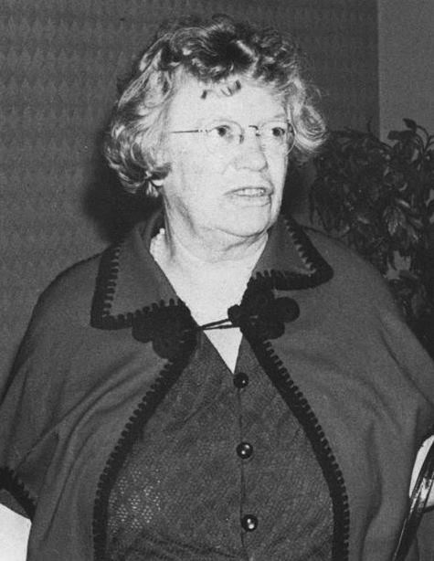 Black and white photo of older white woman with glasses, looking off camera